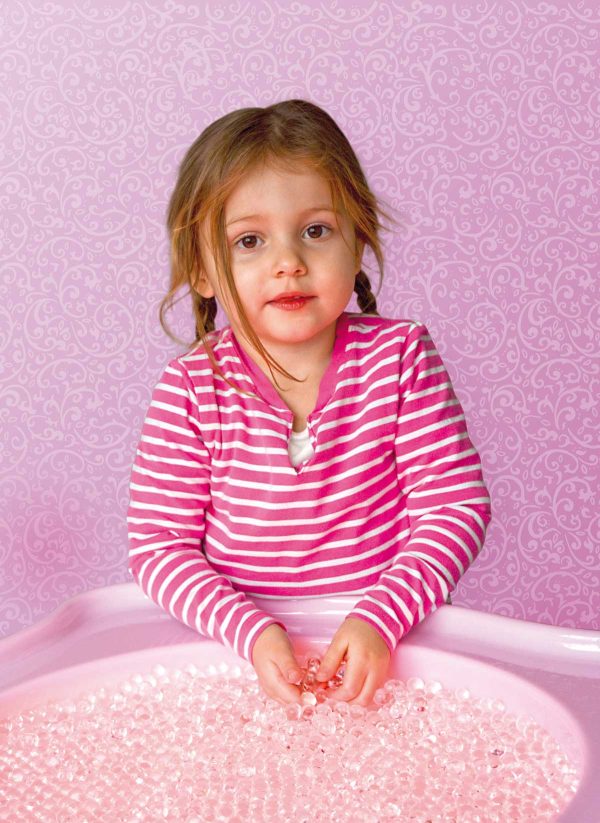 Kind greift in ein Becken voll von Sensorik Perlen