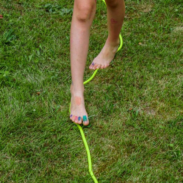 Kind balanciert auf einem in der Wiese liegenden Seil